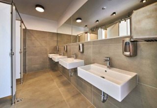 Modern restroom at Camping Stella Maris in Istria, Croatia, with tiled walls, mirrors, and white sinks.