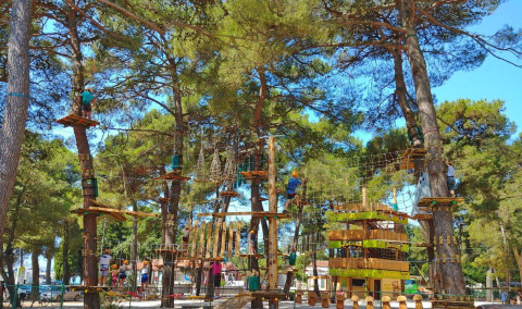 Parque de aventuras en Camping Stella Maris en Istria, Croacia, con personas trepando árboles y disfrutando.