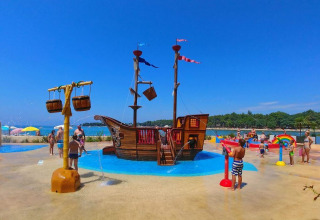 Niños jugando en una zona de juegos acuáticos con barco pirata en Camping Stella Maris, Istria, Croacia, bajo el sol.