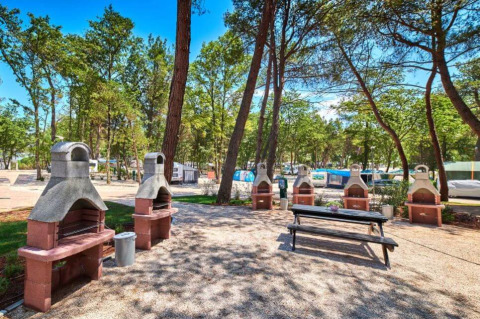 Area barbecue all'aperto con diversi barbecue e tavolo da picnic al Camping Stella Maris, Istria, Croazia.