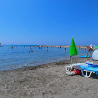 Playa con sombrillas, tumbonas y personas nadando cerca de Umag, Istria, Croacia, en un día soleado.