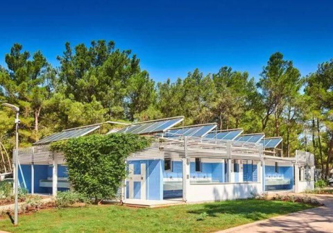 Edificio moderno con paneles solares en Camping Stella Maris, parque vacacional en Istria, Croacia, rodeado de árboles.