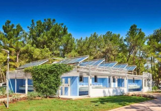 Edificio moderno con pannelli solari al Camping Stella Maris, parco vacanze in Istria, Croazia, circondato da alberi.