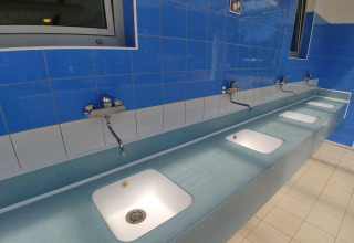 Fila di lavandini moderni sotto piastrelle blu al Camping Stella Maris, un villaggio vacanze in Istria, Croazia.