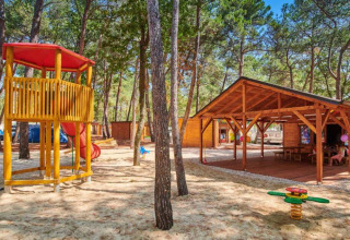 Legeplads og træhytter ved Camping Stella Maris, Istrien, Kroatien, omringet af fyrretræer.