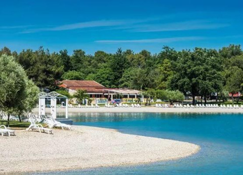Beach with white loungers and clear water at Camping Stella Maris holiday park, Istria, Croatia.