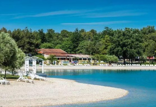 Playa con tumbonas blancas y agua cristalina en el Camping Stella Maris, Istria, Croacia.