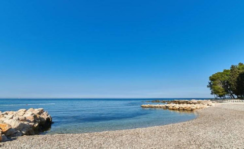 Belle vue sur la plage de galets du Camping Stella Maris en Istrie, Croatie, sous un ciel bleu clair.