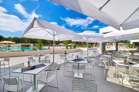 Terraza exterior con sombrillas blancas y asientos modernos en Camping Stella Maris, parque vacacional en Istria, Croacia.