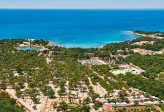 Aerial view of Camping Stella Maris holiday park in Istria, Croatia, with lush trees, buildings and blue sea.