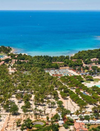 Vista aerea del Camping Stella Maris in Istria, Croazia, circondato da verde, edifici e mare blu.