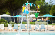 Vandlegeplads ved swimmingpool med farverige spande og palme under solrige omgivelser på Camping Stella Maris.