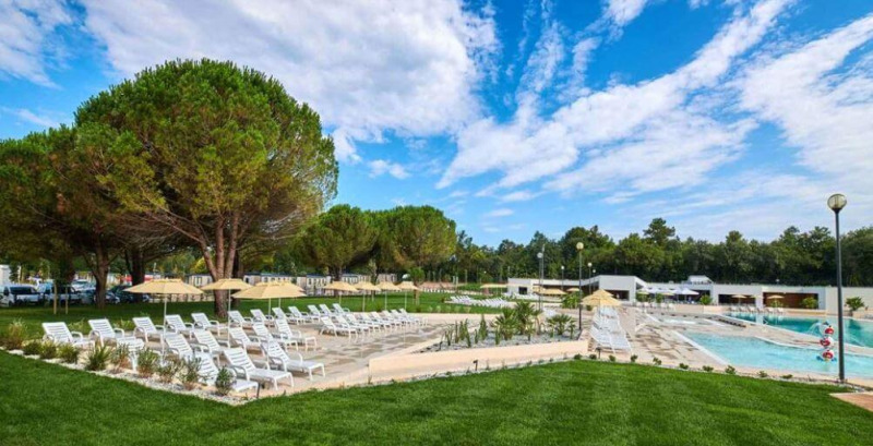 Outdoor pool area with sun loungers, umbrellas, and lush trees at Camping Stella Maris in Istria, Croatia.