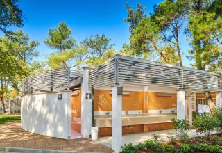 Moderne sanitetsfaciliteter på Camping Stella Maris i Istrien, Kroatien, omgivet af grønne træer og blå himmel.
