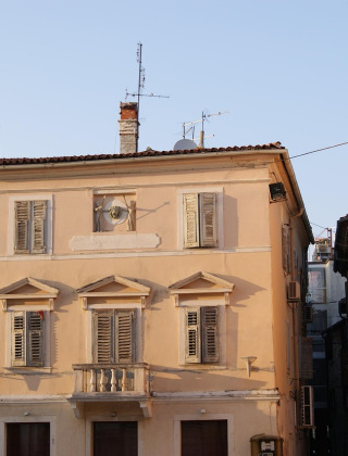 Casa antigua con persianas cerradas en una calle estrecha de Umag, Istria, Croacia, al atardecer.