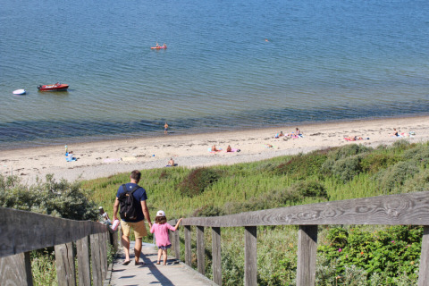 Padre e hija bajan por una escalera hacia la playa en Toftum Bjerge Camping, Región Central de Dinamarca.