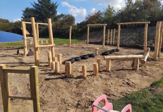 Buitenspeelplaats bij Toftum Bjerge Camping in Denemarken met houten balanceertoestellen.