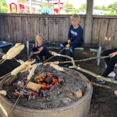 Niños asando pan en palos sobre una fogata en Toftum Bjerge Camping en la región central de Dinamarca.