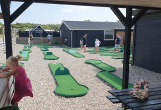 Campo de mini golf en Toftum Bjerge Camping, familias y niños divirtiéndose al aire libre.