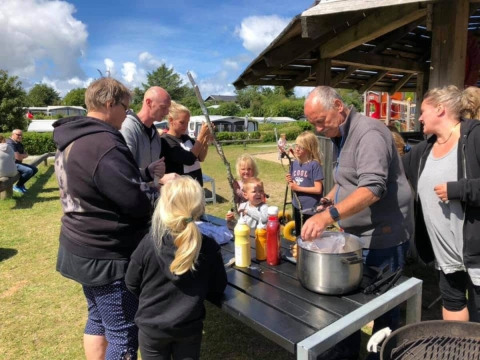 Gezinnen genieten buiten van een barbecue op Toftum Bjerge Camping, Midden-Jutland, Denemarken.