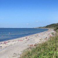Personas tomando sol y nadando en una playa tranquila con dunas junto a Struer, Región Central de Dinamarca.