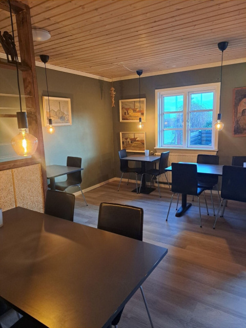 Salle à manger de Toftum Bjerge Camping avec tables modernes, plafond en bois et éclairage doux.