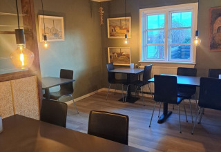 Dining room at Toftum Bjerge Camping featuring modern tables, wood ceiling and soft pendant lighting.