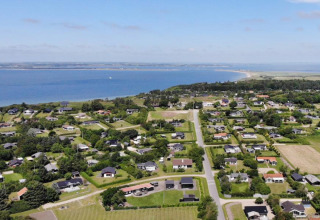 Vista aérea del parque vacacional Toftum Bjerge Camping con cabañas y vista al mar en Dinamarca Central.