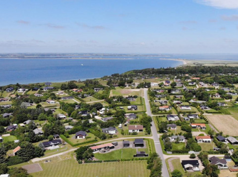 Vista aérea del parque vacacional Toftum Bjerge Camping con cabañas y vista al mar en Dinamarca Central.