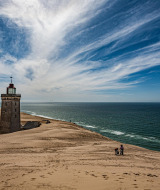Faro rodeado de dunas y el mar visto cerca de Struer, Región Central de Dinamarca, bajo un cielo espectacular.