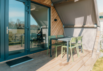 Outdoor patio with green chairs and table at the Big Lodge, Holiday park De Boshoek, Netherlands.