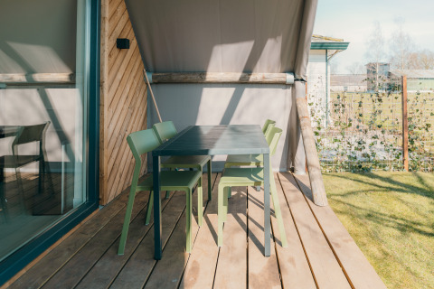 Buitenterras met groene stoelen en zwarte tafel aan Big lodge op Holiday park De Boshoek, Nederland.