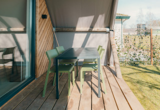 Terraza exterior con sillas verdes y mesa negra en Big Lodge del Holiday park De Boshoek, Países Bajos.