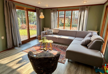 Luminoso soggiorno al Cozy Lodge, Bungalowpark Het Verscholen Dorp, Paesi Bassi, con divano e vista giardino.