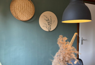 Moderne setting in Cozy Lodge, Bungalowpark Het Verscholen Dorp, Nederland, met lamp en wandkunst.
