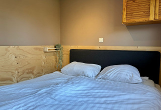 Gezellige slaapkamer met dubbel bed in Cozy Lodge, Bungalowpark Het Verscholen Dorp, Nederland, modern ingericht.