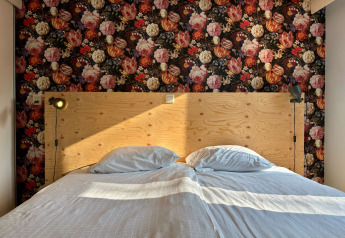 Double bed at Cozy Lodge in Bungalowpark Het Verscholen Dorp, Netherlands, floral wallpaper, wooden headboard.
