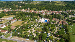 Luchtfoto van Camping Le Château vakantiepark in Auvergne-Rhône-Alpes, Frankrijk, met veel bomen en zwembad.