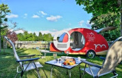 Udendørs scene på Camping Le Château i Auvergne-Rhône-Alpes, Frankrig, med campingvogn og picnicopstilling.