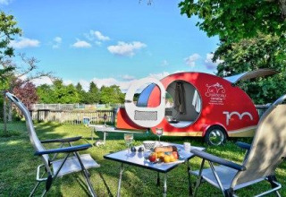 Udendørs scene på Camping Le Château i Auvergne-Rhône-Alpes, Frankrig, med campingvogn og picnicopstilling.