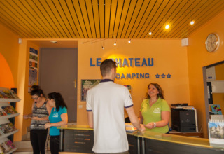 Reception al Camping Le Château con staff e ospiti nel parco vacanze di Alvernia-Rodano-Alpi, Francia.