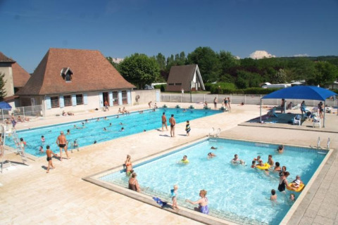 Piscinas al aire libre con niños y adultos en Camping Le Château, un parque vacacional en Auvergne-Rhône-Alpes, Francia.