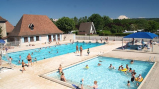 Piscine all'aperto con bambini e adulti al Camping Le Château, villaggio turistico in Alvernia-Rodano-Alpi, Francia.
