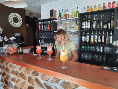 Camarera preparando cócteles coloridos en el bar de Camping Le Château, Auvergne-Rhône-Alpes, Francia.