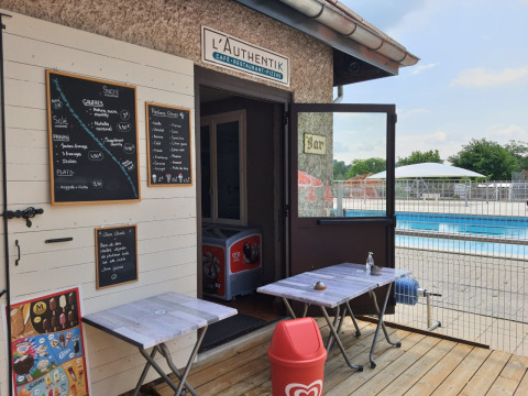 Caffè all'aperto e snack bar vicino alla piscina al Camping Le Château, Auvergne-Rhône-Alpes, Francia.