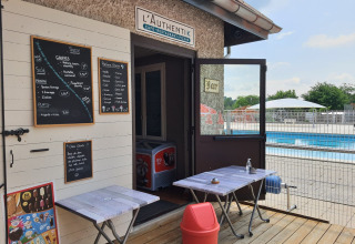 Caffè all'aperto e snack bar vicino alla piscina al Camping Le Château, Auvergne-Rhône-Alpes, Francia.
