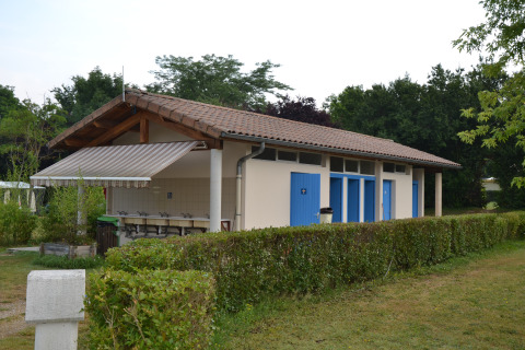 Gebäude mit blauen Türen und überdachten Waschplätzen im Camping Le Château in Auvergne-Rhône-Alpes, Frankreich.