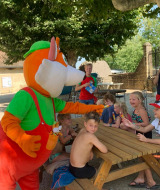 Niños se divierten con una mascota colorida en una mesa de picnic en Camping Le Château, Auvergne-Rhône-Alpes.