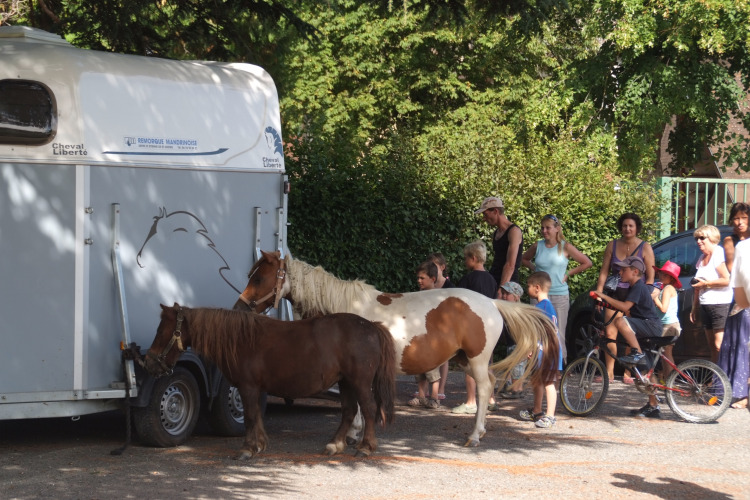 Folk samles ved ponyer og en hestetrailer på Camping Le Château i Auvergne-Rhône-Alpes, Frankrig.
