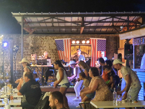 Abendveranstaltung mit Live-Countryband und tanzenden Gästen im Camping Le Château, Auvergne-Rhône-Alpes, Frankreich.